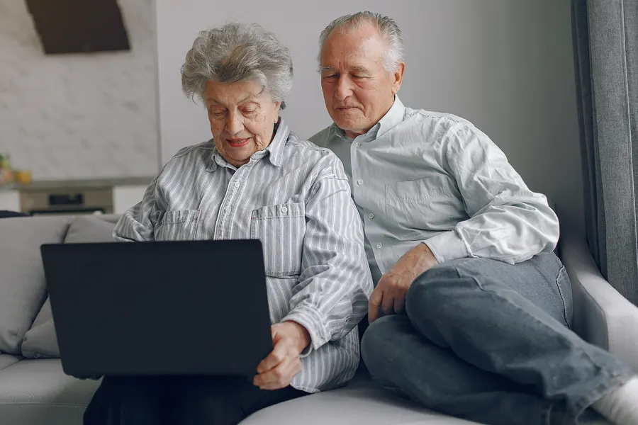 Coppia di pensionati usa il portatile a casa